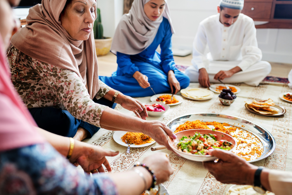 group of men and women sitting together and eating during Ramadan