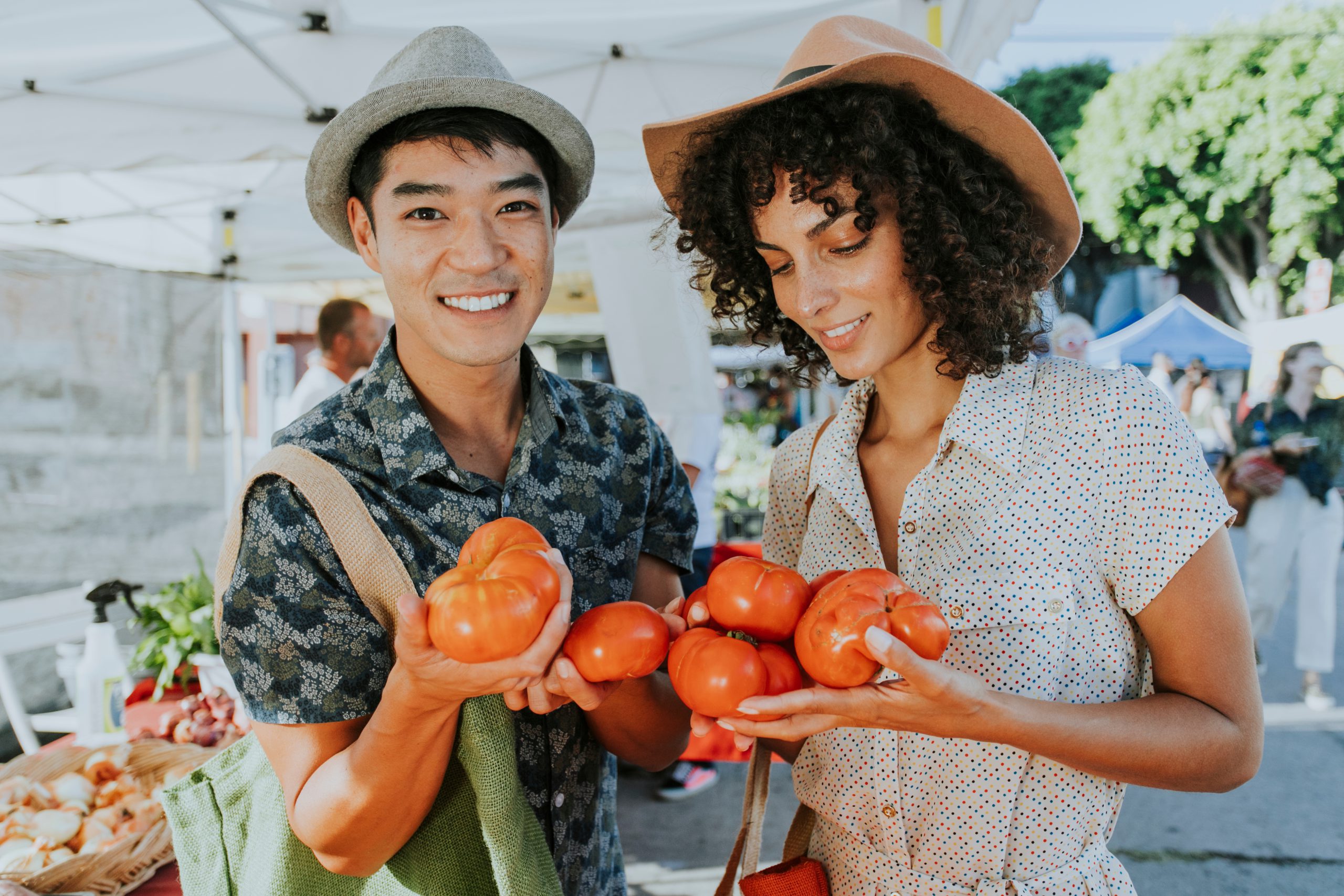 two-shoppers-holding-tomatoes-at-a-farmers-market